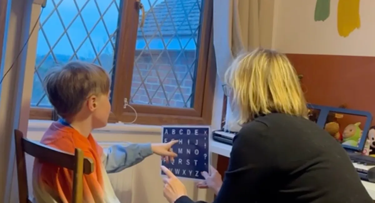 A child pointing to letters on an S2C letterboard during a session