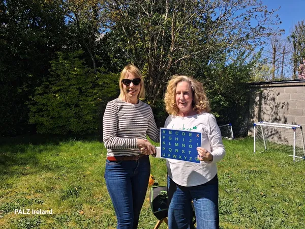 Sofia holding a letterboard outdoors, with Elizabeth Vosseller