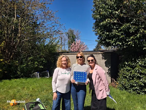 Sofia holding a letterboard outdoors, with Elizabeth Vosseller and Anna from PALZ Ireland